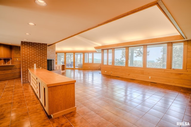 7 Sharon Ln, Fulton, IL 61252 - kitchen featuring a brick fireplace, light countertops, wooden walls, open floor plan, and light tile patterned floors