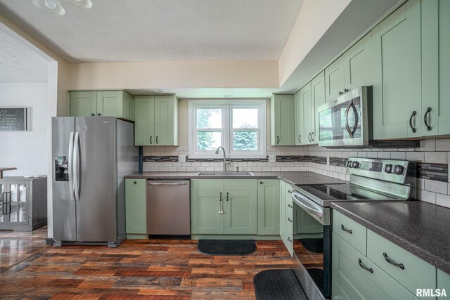 3436 Ridge Ct, Davenport, IA 52806 - kitchen featuring green cabinets, appliances with stainless steel finishes, dark wood-style floors, and tasteful backsplash