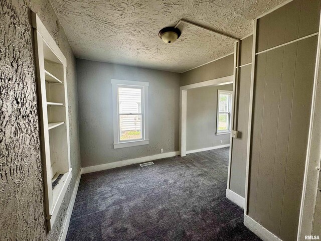 1150 14th Ave, Moline, IL 61265 - empty room with dark carpet and a textured ceiling