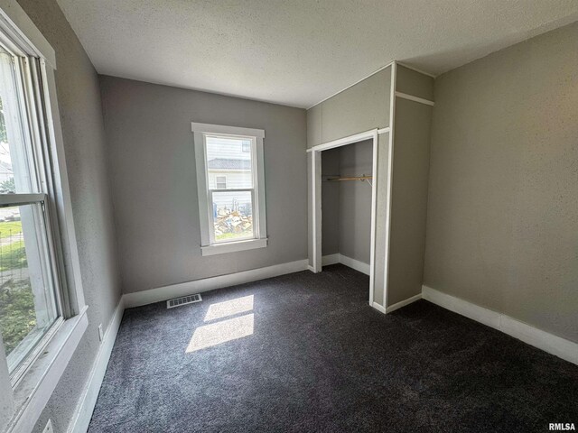1150 14th Ave, Moline, IL 61265 - unfurnished bedroom featuring dark colored carpet, a textured ceiling, and a closet