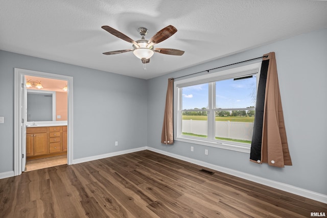 6365 Friendship Path, Bettendorf, IA 52722 - unfurnished bedroom with dark wood-type flooring, connected bathroom, ceiling fan, and a textured ceiling