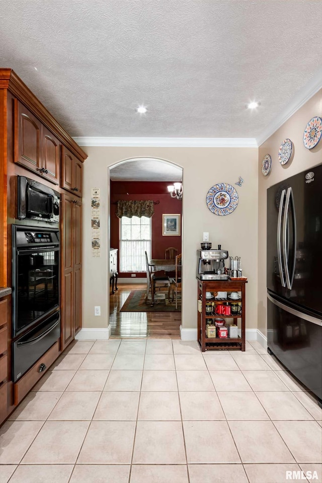 1300 W Brewster Rd, Herrin, IL 62948 - kitchen with black appliances, a warming drawer, arched walkways, ornamental molding, and light tile patterned floors