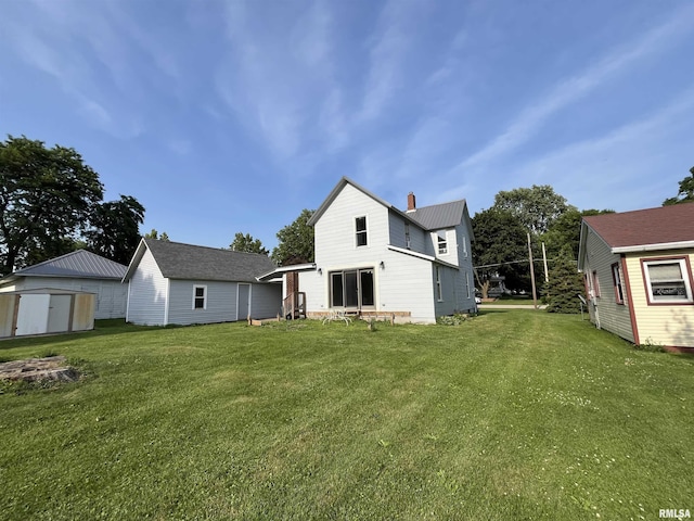 212 S E St, Cambridge, IL 61238 - back of house featuring a storage unit, a lawn, a chimney, and a metal roof