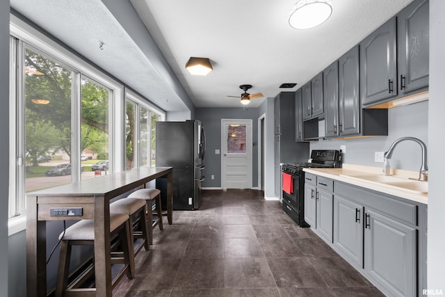 409 W 30th Ave, Milan, IL 61264 - kitchen with gas stove, freestanding refrigerator, gray cabinetry, light countertops, and ceiling fan