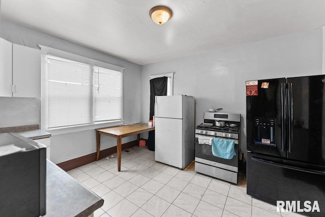 1625 14 1/2 St, Rock Island, IL 61201 - kitchen featuring black fridge with ice dispenser, freestanding refrigerator, stainless steel gas range, white cabinetry, and light tile patterned floors