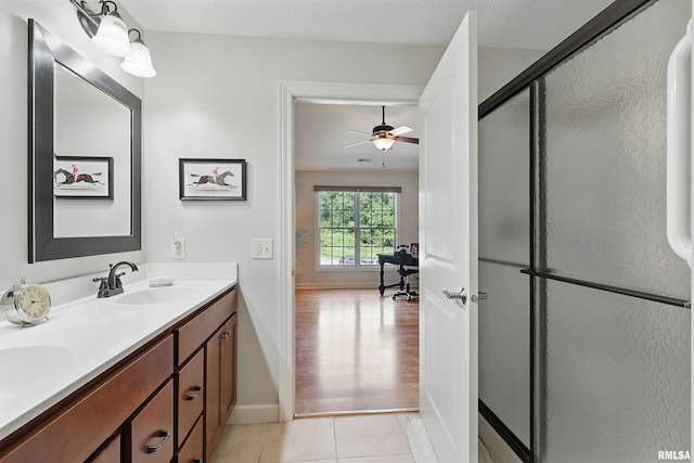 1237 Kimberly Rd, Bettendorf, IA 52722 - bathroom featuring double vanity, a shower stall, tile patterned flooring, and a ceiling fan