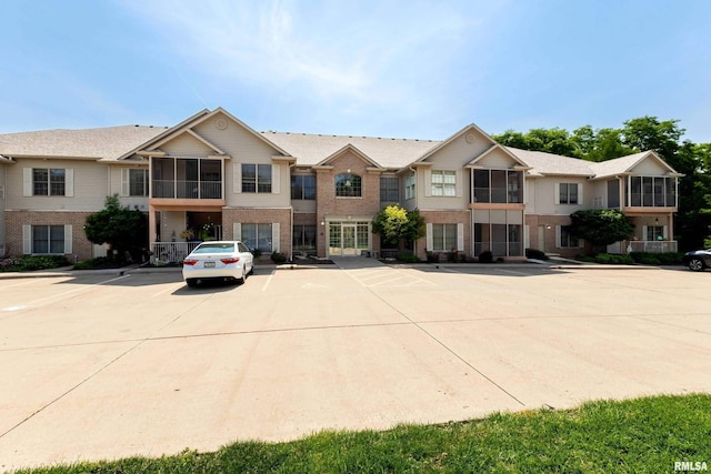 1237 Kimberly Rd, Bettendorf, IA 52722 - view of front facade featuring brick siding, uncovered parking, and a sunroom