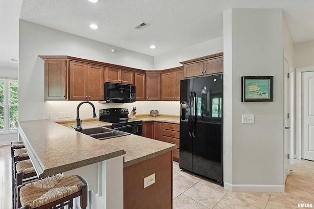 1237 Kimberly Rd, Bettendorf, IA 52722 - kitchen with black appliances, a peninsula, a breakfast bar area, brown cabinets, and light tile patterned floors