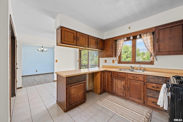 3796 160th St, Bryant, IA 52727 - kitchen with stainless steel gas range oven, a chandelier, light countertops, a peninsula, and brown cabinetry