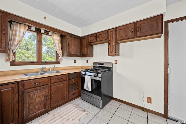 3796 160th St, Bryant, IA 52727 - kitchen with stainless steel gas range oven, light countertops, light tile patterned floors, and dark brown cabinets