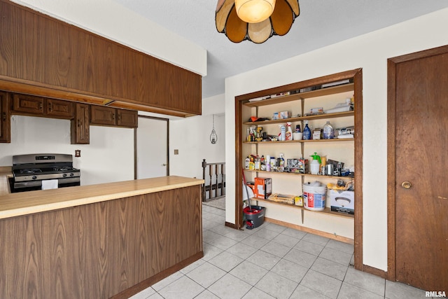 3796 160th St, Bryant, IA 52727 - kitchen featuring stainless steel gas range, light countertops, a peninsula, light tile patterned flooring, and a ceiling fan