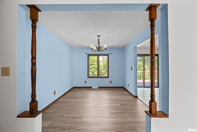 3796 160th St, Bryant, IA 52727 - unfurnished dining area featuring wood finished floors, a chandelier, and a textured ceiling
