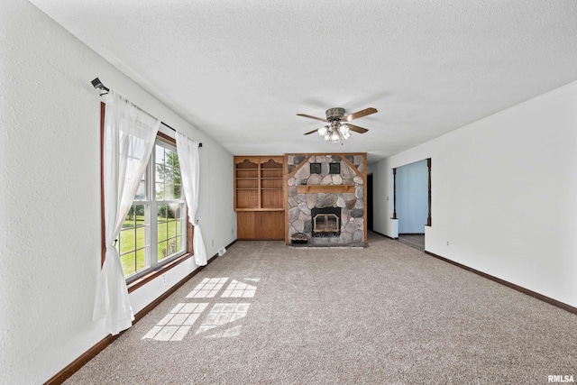 3796 160th St, Bryant, IA 52727 - unfurnished living room with a textured ceiling, carpet floors, a ceiling fan, and a fireplace