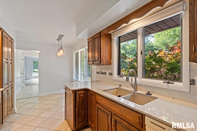 4319 7th Ave, Moline, IL 61265 - kitchen featuring light tile patterned flooring, brown cabinetry, decorative light fixtures, light stone counters, and decorative backsplash