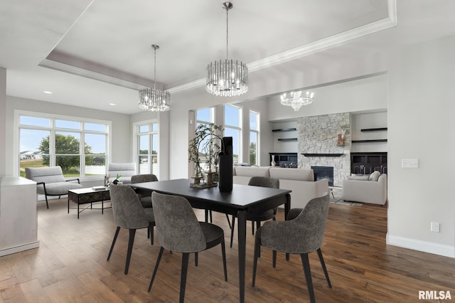 5541 Pigeon Creek Rd, Bettendorf, IA 52722 - dining room featuring a tray ceiling, hardwood / wood-style flooring, a chandelier, crown molding, and a stone fireplace