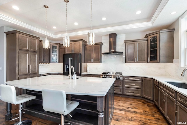 5541 Pigeon Creek Rd, Bettendorf, IA 52722 - kitchen with wall chimney exhaust hood, high quality fridge, a raised ceiling, an island with sink, and a breakfast bar area