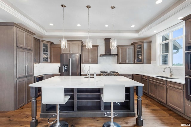 5541 Pigeon Creek Rd, Bettendorf, IA 52722 - kitchen with high end fridge, wall chimney exhaust hood, a raised ceiling, a breakfast bar area, and crown molding