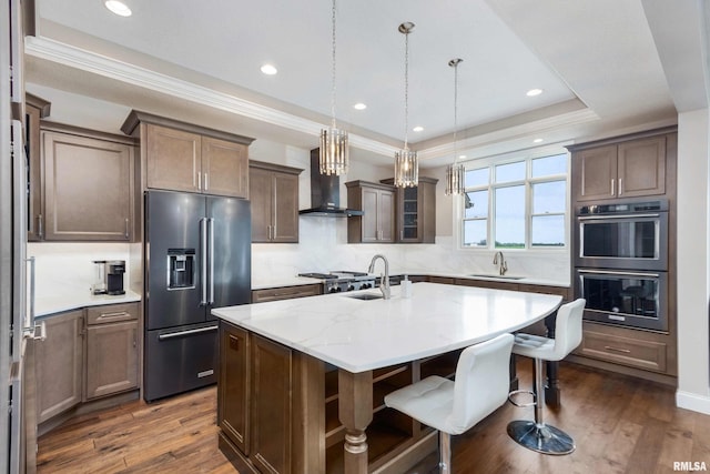 5541 Pigeon Creek Rd, Bettendorf, IA 52722 - kitchen featuring high end fridge, double oven, wall chimney range hood, dark wood-style flooring, and a kitchen island with sink