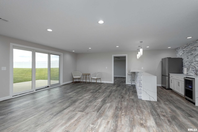 5541 Pigeon Creek Rd, Bettendorf, IA 52722 - unfurnished living room with wine cooler, wood finished floors, and recessed lighting