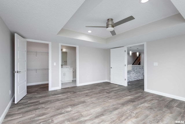 5541 Pigeon Creek Rd, Bettendorf, IA 52722 - unfurnished bedroom featuring wood finished floors, a raised ceiling, ensuite bathroom, a closet, and recessed lighting