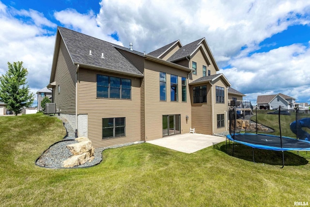 5541 Pigeon Creek Rd, Bettendorf, IA 52722 - back of house featuring a patio, a trampoline, a shingled roof, and a lawn