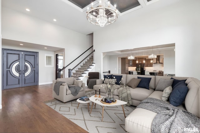 5541 Pigeon Creek Rd, Bettendorf, IA 52722 - living room featuring a chandelier, a towering ceiling, stairs, coffered ceiling, and wood finished floors