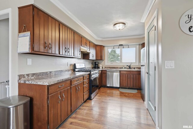 3770 153rd St, Blue Grass, IA 52726 - kitchen with appliances with stainless steel finishes, under cabinet range hood, light wood finished floors, brown cabinets, and crown molding