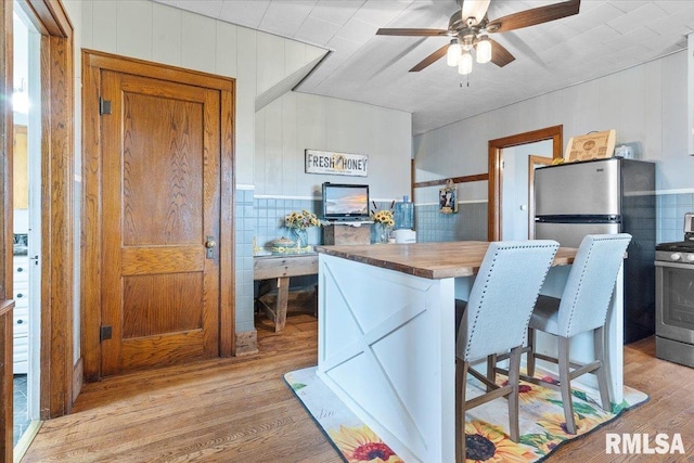 3292 110th St, Stockton, IA 52769 - kitchen with stainless steel appliances, ceiling fan, light wood-type flooring, wood walls, and butcher block counters