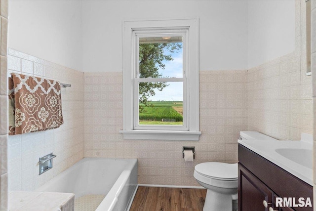 3292 110th St, Stockton, IA 52769 - bathroom with vanity, tile walls, a tub, wood finished floors, and wainscoting