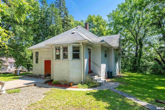 3123 Commodore St, Davenport, IA 52802 - bungalow featuring entry steps, stucco siding, a front lawn, a chimney, and roof with shingles