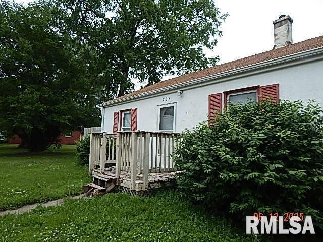 708 3rd St, Buffalo, IA 52728 - view of side of home featuring a deck, a lawn, and stucco siding