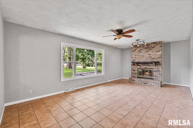 3611 75th St, Moline, IL 61265 - unfurnished living room featuring ceiling fan, light tile patterned flooring, a brick fireplace, and rail lighting