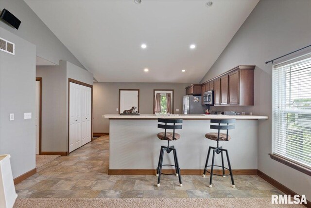 6234 Mississippi Ave, Davenport, IA 52807 - kitchen featuring stainless steel appliances, lofted ceiling, stone finish flooring, a peninsula, and a kitchen bar