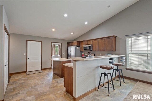 6234 Mississippi Ave, Davenport, IA 52807 - kitchen with appliances with stainless steel finishes, a peninsula, light countertops, a kitchen bar, and brown cabinets