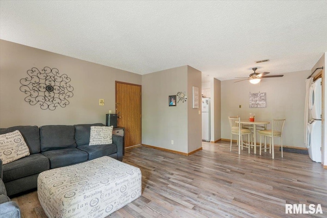 4725 Kynnelworth Dr Unit 8, Bettendorf, IA 52722 - living area with wood finished floors, ceiling fan, stacked washing machine and dryer, and a textured ceiling