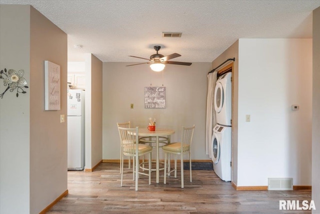 4725 Kynnelworth Dr Unit 8, Bettendorf, IA 52722 - dining area featuring estacked washer and dryer, a ceiling fan, wood finished floors, and a textured ceiling
