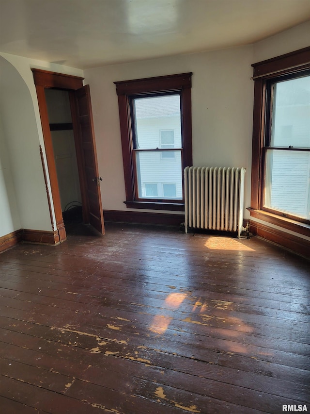 606 Meridian St Unit 1 & 2, Tipton, IA 52772 - unfurnished bedroom with radiator, hardwood / wood-style floors, multiple windows, and arched walkways
