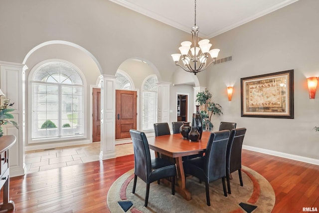 11 Sandstone Ct, Le Claire, IA 52753 - dining room featuring ornate columns, arched walkways, hardwood / wood-style floors, a chandelier, and a high ceiling