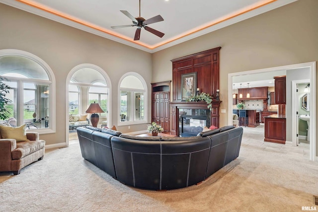 11 Sandstone Ct, Le Claire, IA 52753 - living room featuring light colored carpet, a ceiling fan, ornamental molding, a towering ceiling, and a multi sided fireplace