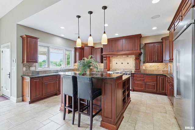 11 Sandstone Ct, Le Claire, IA 52753 - kitchen with high quality appliances, a kitchen island, tasteful backsplash, pendant lighting, and dark stone counters