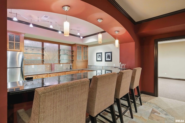 11 Sandstone Ct, Le Claire, IA 52753 - kitchen featuring freestanding refrigerator, a kitchen breakfast bar, light colored carpet, glass insert cabinets, and ornamental molding