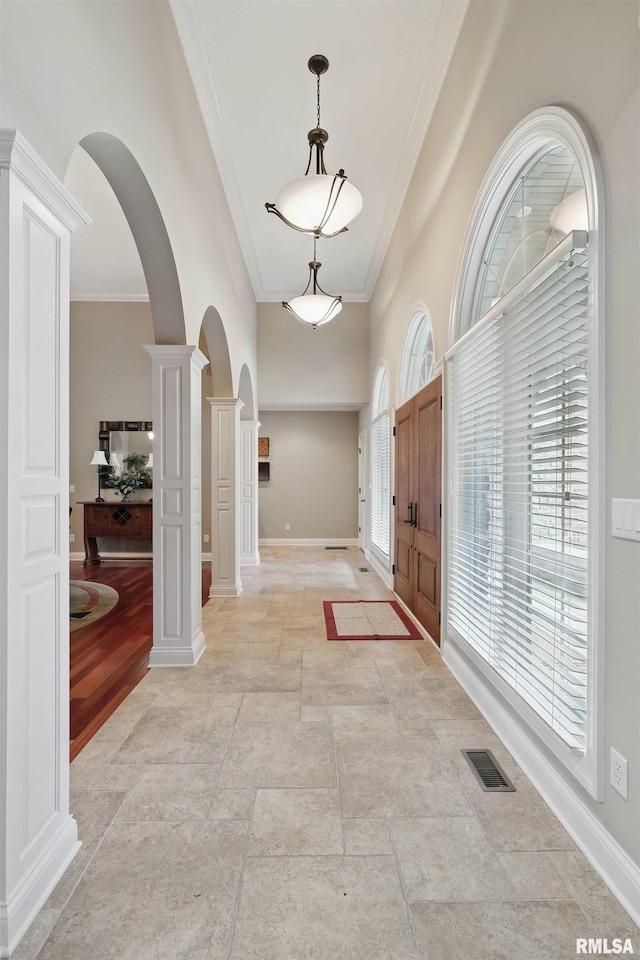 11 Sandstone Ct, Le Claire, IA 52753 - entryway with arched walkways, decorative columns, ornamental molding, a towering ceiling, and light stone finish floors