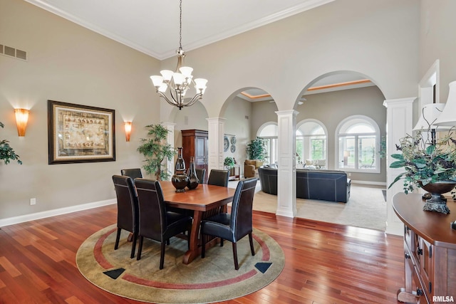 11 Sandstone Ct, Le Claire, IA 52753 - dining space with decorative columns, arched walkways, wood finished floors, a high ceiling, and a chandelier