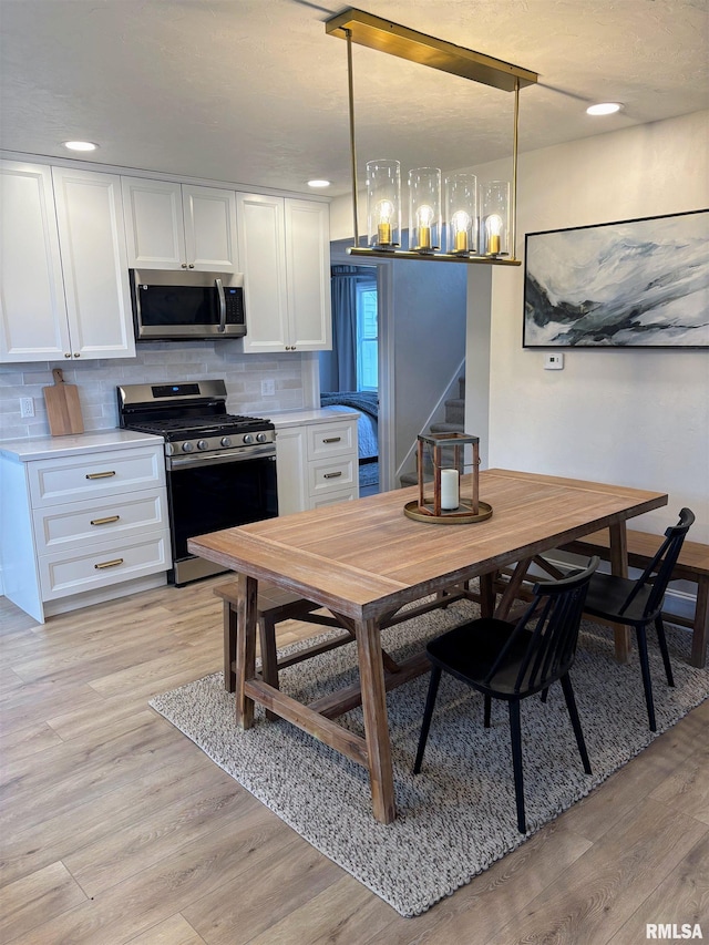 323 N Vail St, Geneseo, IL 61254 - kitchen featuring appliances with stainless steel finishes, light wood-style floors, white cabinets, decorative backsplash, and light countertops