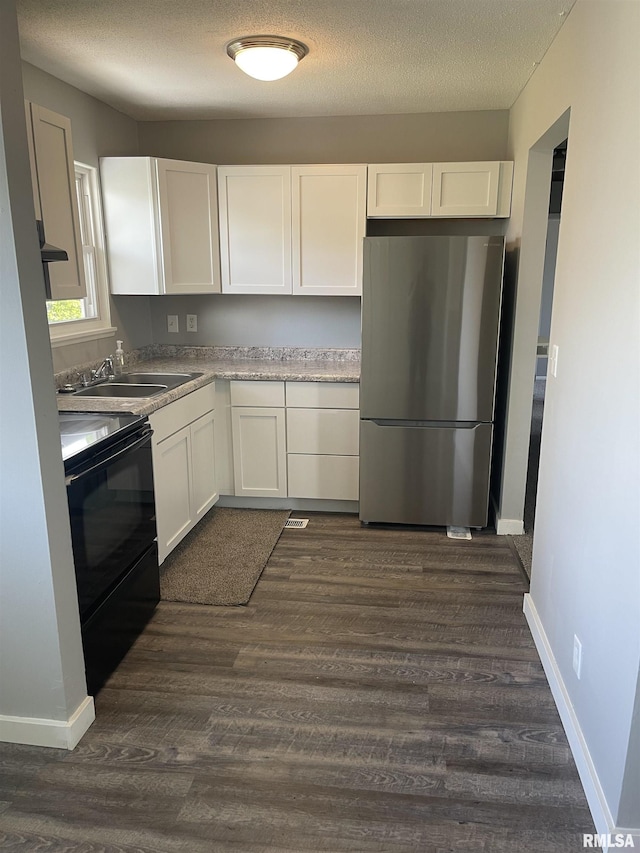 1951 Bristol Dr, Bettendorf, IA 52722 - kitchen with freestanding refrigerator, black range with electric cooktop, white cabinetry, dark wood-style flooring, and a textured ceiling