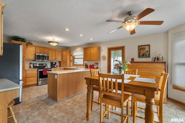 1010 Meadows Cir, Bettendorf, IA 52722 - kitchen featuring appliances with stainless steel finishes, light countertops, a ceiling fan, recessed lighting, and a kitchen island