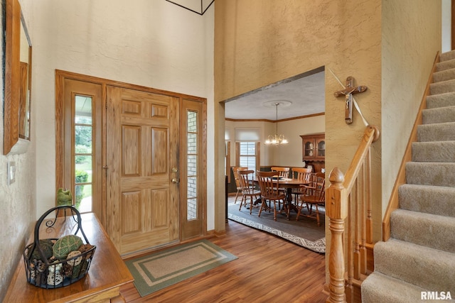 1010 Meadows Cir, Bettendorf, IA 52722 - entryway featuring wood finished floors, a textured wall, stairway, a chandelier, and ornamental molding