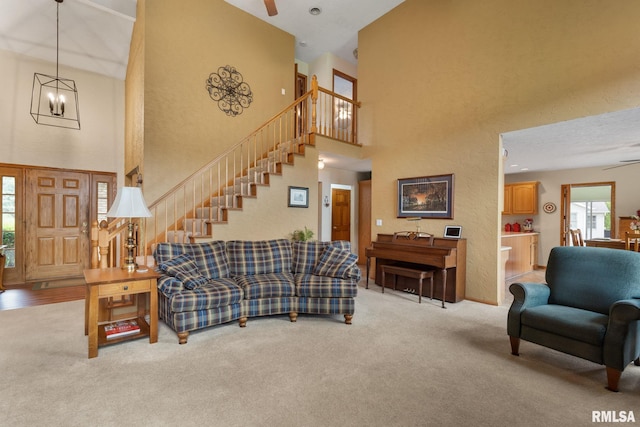 1010 Meadows Cir, Bettendorf, IA 52722 - living room featuring a ceiling fan, a high ceiling, stairway, carpet floors, and a chandelier