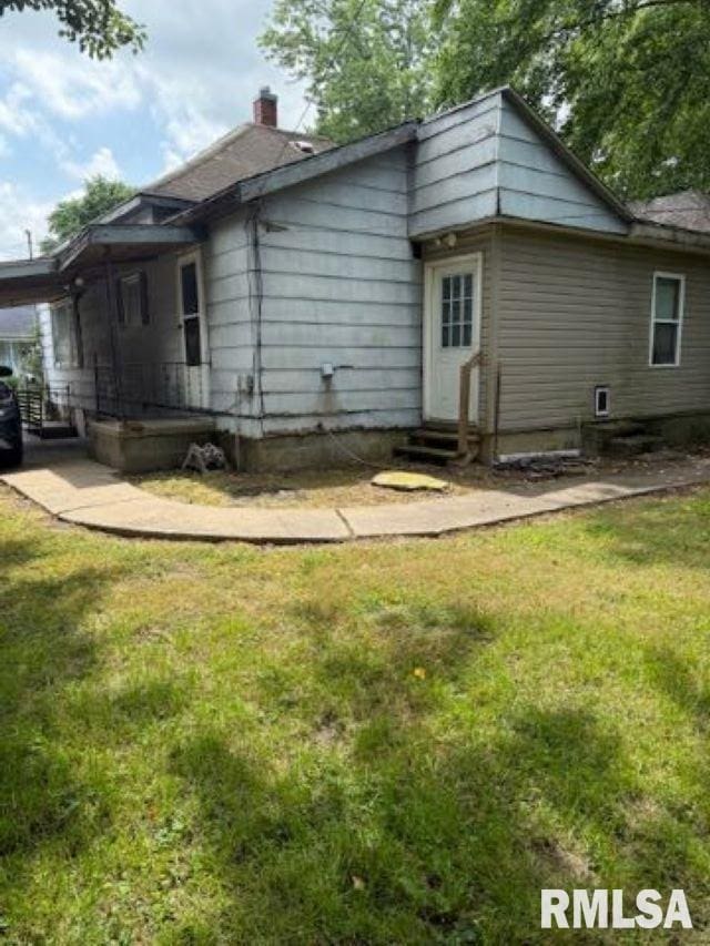 313 E 4th St, West Frankfort, IL 62896 - back of house with entry steps, a yard, a chimney, and an attached carport