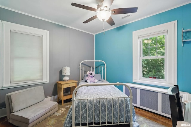 850 27th St, Rock Island, IL 61201 - bedroom featuring crown molding, radiator heating unit, wood finished floors, a ceiling fan, and a decorative wall
